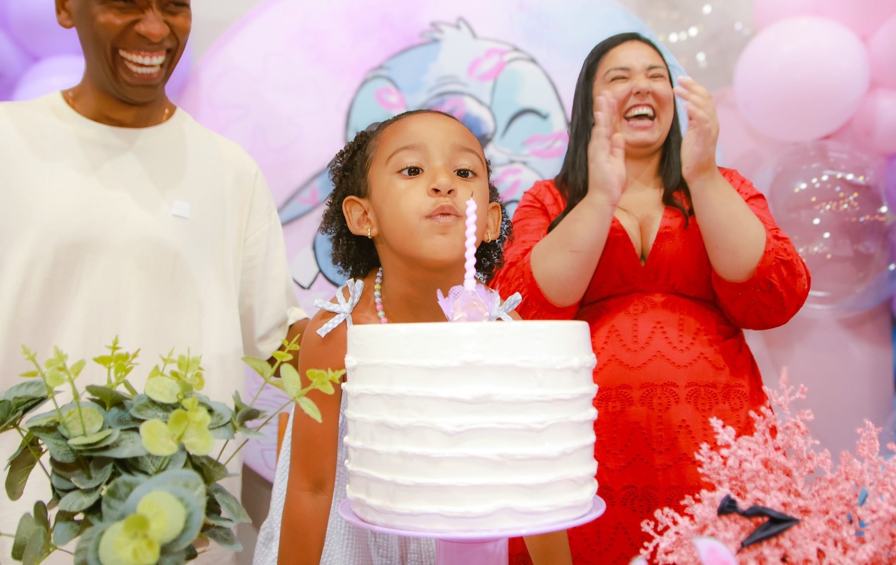 Aniversariante com os pais no momento do parabéns